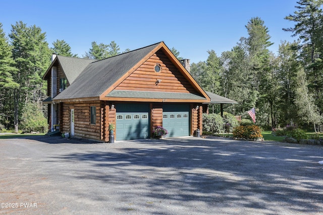 view of side of property with a shingled roof, log exterior, a chimney, and a detached garage