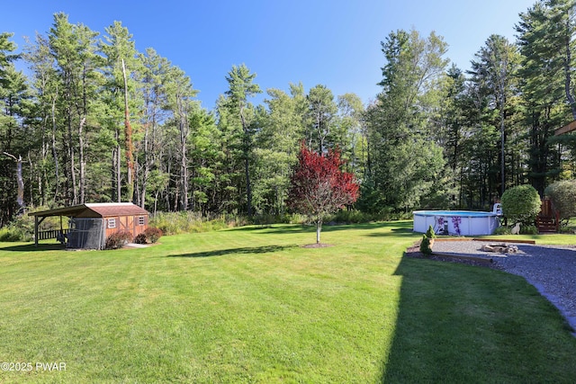view of yard featuring a storage unit, an outbuilding, and an outdoor pool