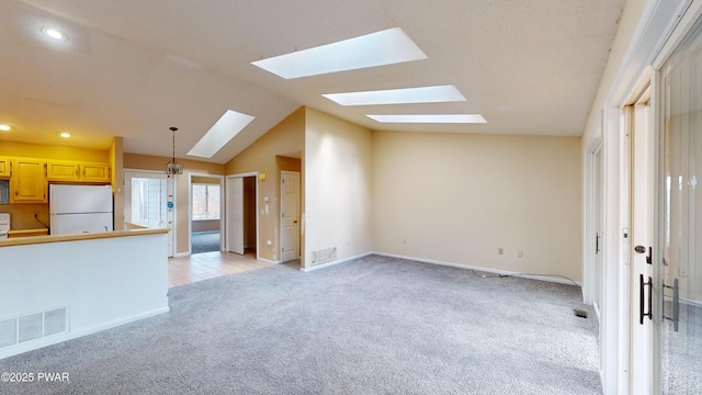 unfurnished living room with light colored carpet and lofted ceiling with skylight