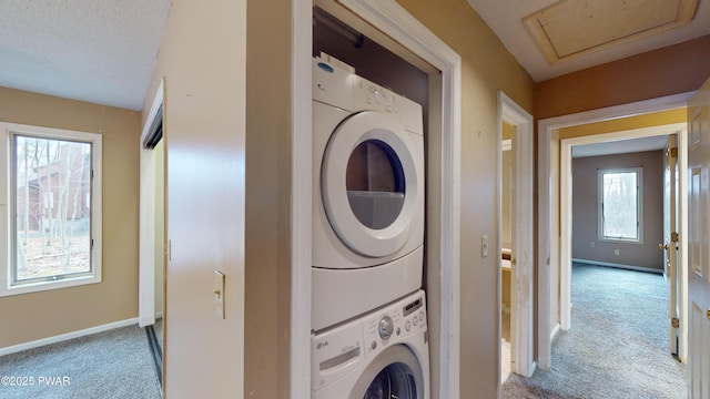 laundry room featuring light colored carpet, a wealth of natural light, and stacked washer and dryer