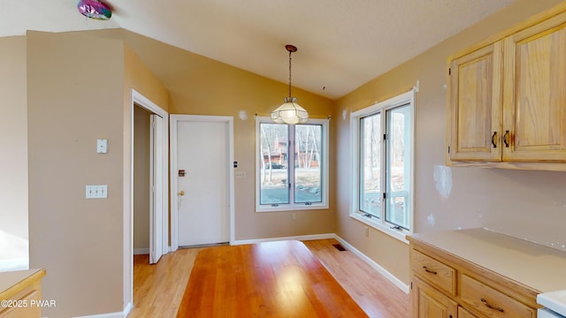 unfurnished dining area with lofted ceiling and light hardwood / wood-style flooring