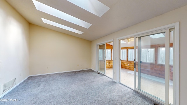 spare room with vaulted ceiling with skylight and carpet