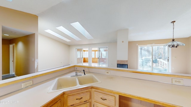 kitchen featuring a skylight, light brown cabinets, pendant lighting, and sink