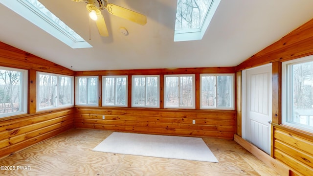 unfurnished sunroom with ceiling fan, a healthy amount of sunlight, and vaulted ceiling with skylight