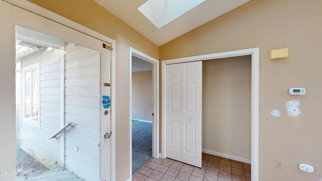 corridor with lofted ceiling with skylight and light tile patterned floors