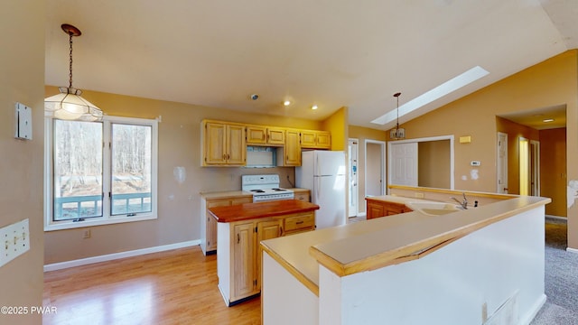 kitchen with white appliances, a center island, lofted ceiling with skylight, and hanging light fixtures