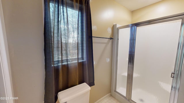 bathroom featuring toilet and a shower with shower door