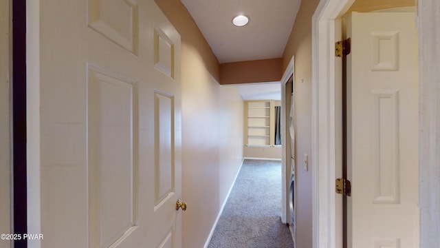 hallway with built in shelves and carpet flooring