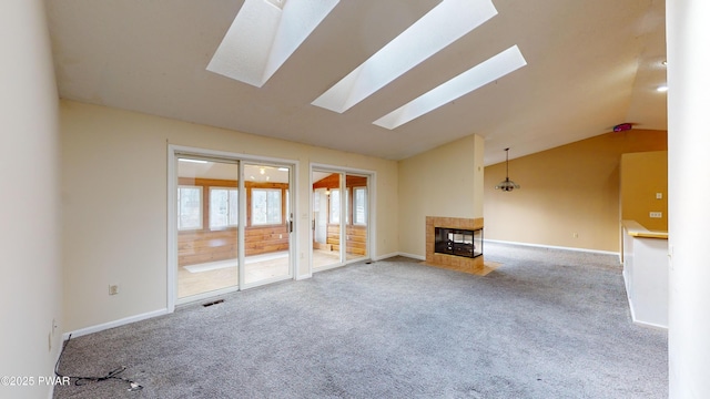 unfurnished living room with a fireplace, vaulted ceiling with skylight, and carpet floors