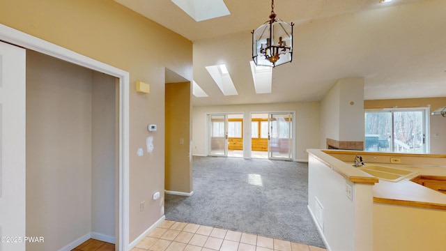 interior space with sink, light carpet, lofted ceiling with skylight, and a notable chandelier