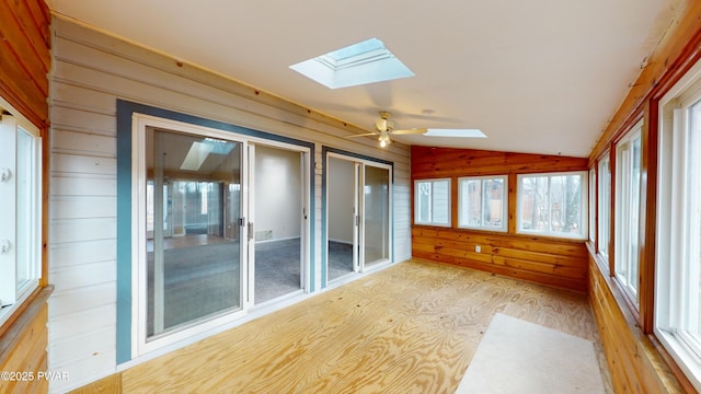 unfurnished sunroom with ceiling fan, lofted ceiling with skylight, and plenty of natural light