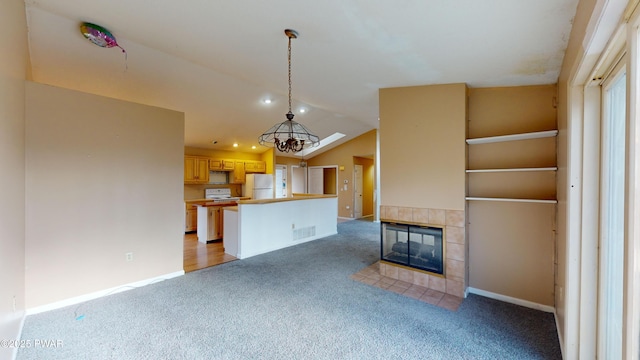 unfurnished living room with an inviting chandelier, a tiled fireplace, vaulted ceiling, and carpet