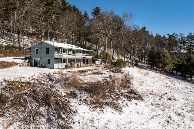 snow covered back of property featuring a wooden deck