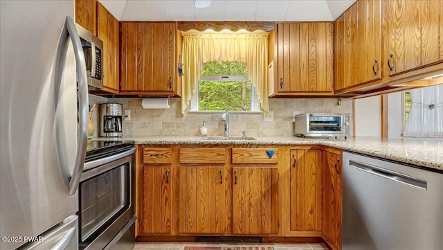 32 White Oak Dr, Lakeville, PA 18438 - kitchen featuring appliances with stainless steel finishes, a sink, decorative backsplash, brown cabinets, and light stone counters