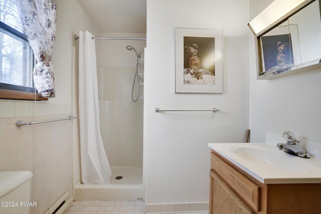 bathroom with vanity, toilet, baseboard heating, walk in shower, and tile walls