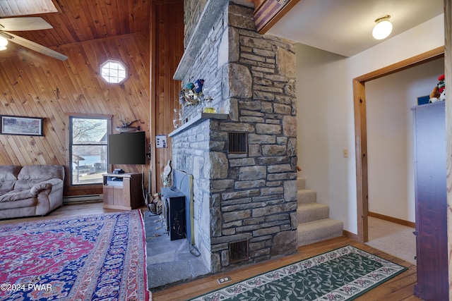 living room featuring wood walls, wooden ceiling, a baseboard heating unit, hardwood / wood-style flooring, and ceiling fan