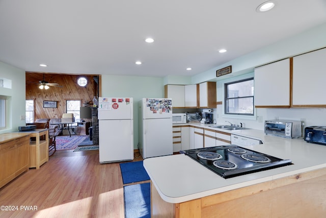 kitchen featuring a wealth of natural light, white appliances, wooden walls, sink, and white cabinets