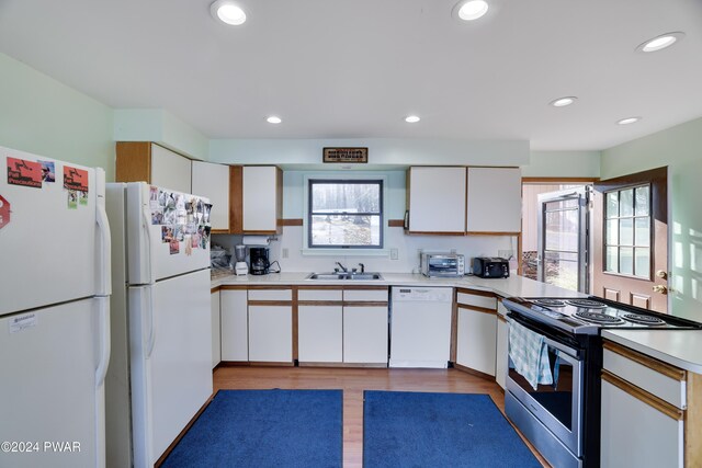 kitchen featuring sink, white cabinets, light hardwood / wood-style floors, and white appliances