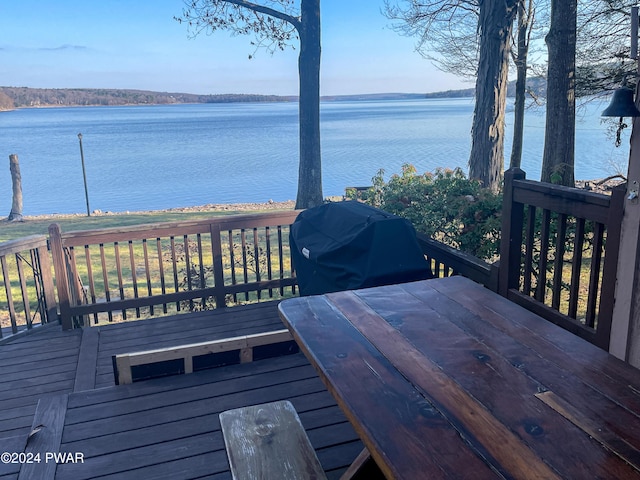 wooden terrace featuring area for grilling and a water view