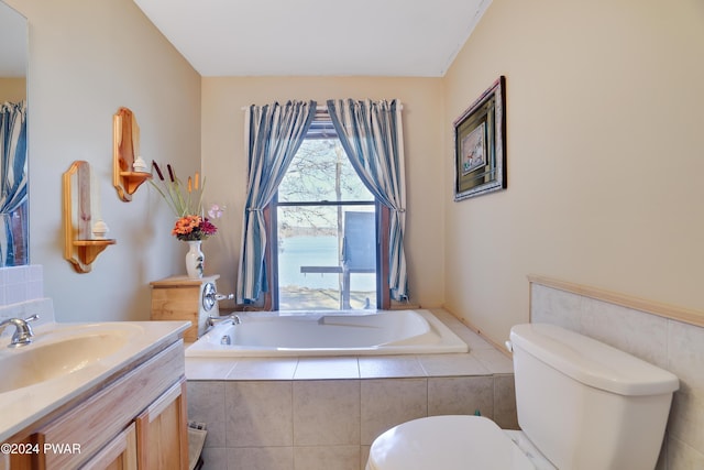 bathroom with tiled bath, vanity, and toilet