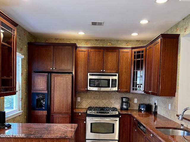 kitchen featuring tasteful backsplash, sink, dark stone counters, and stainless steel appliances