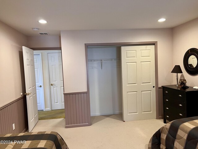 bedroom with light colored carpet, a closet, and wooden walls