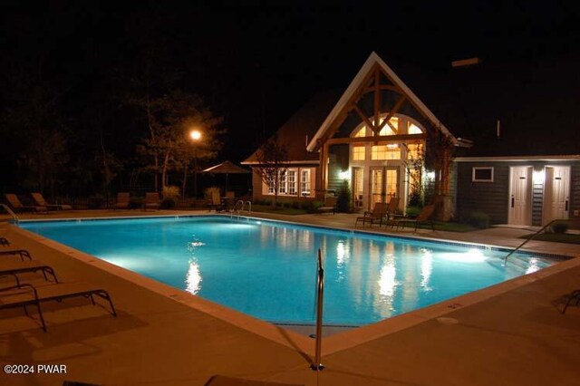 pool at twilight with an outbuilding and a patio