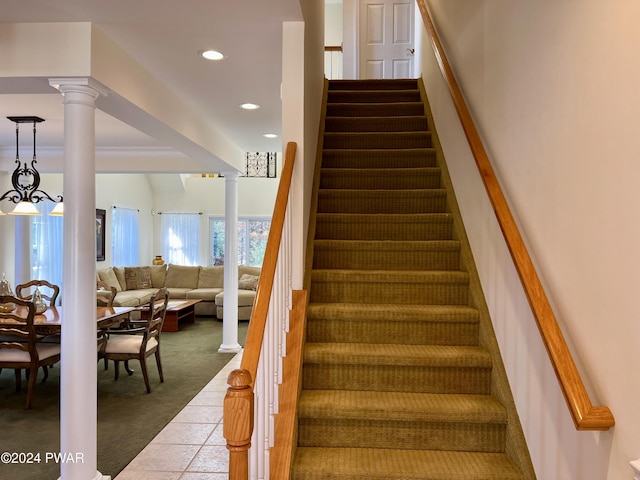 staircase featuring decorative columns and carpet