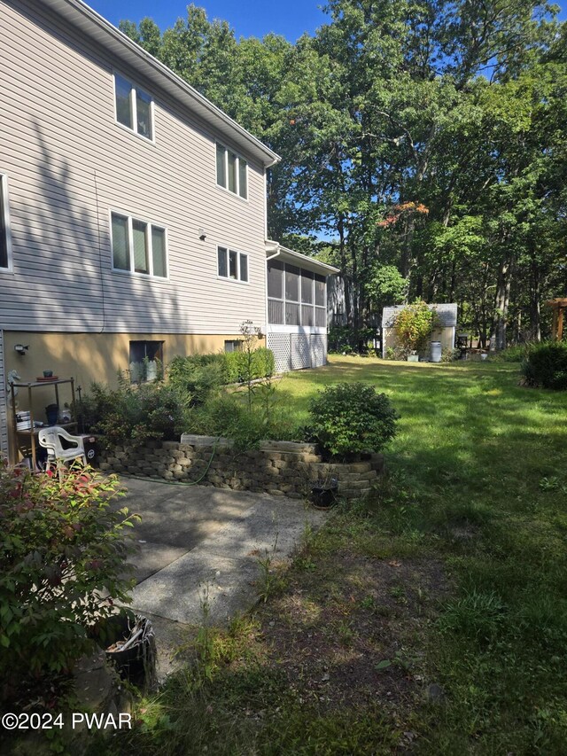 rear view of property featuring a lawn and a sunroom