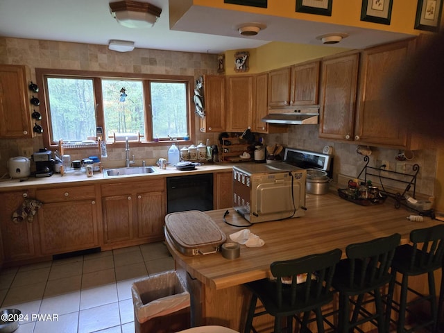 kitchen featuring tasteful backsplash, sink, light tile patterned floors, and black dishwasher