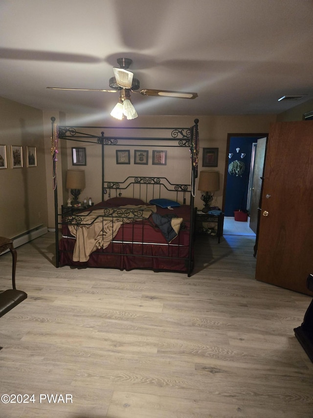 bedroom featuring wood-type flooring, ceiling fan, and a baseboard heating unit