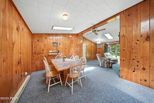 201 Oak Hill Rd, Hawley, PA 18428 - carpeted dining space with a baseboard heating unit, a ceiling fan, wooden walls, a skylight, and a wall unit AC