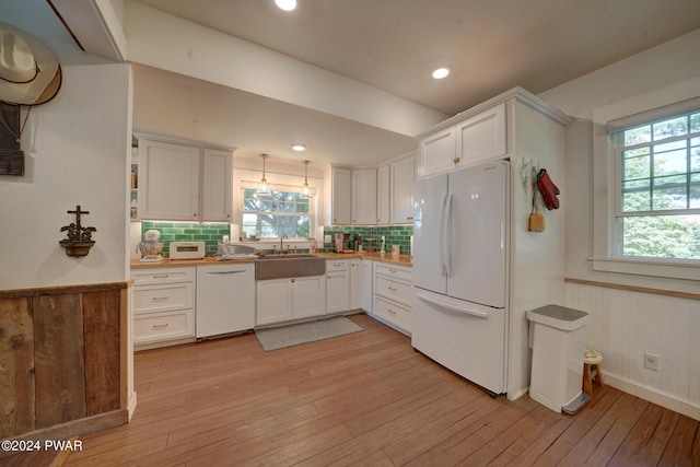 kitchen featuring white appliances, backsplash, white cabinets, sink, and light hardwood / wood-style flooring