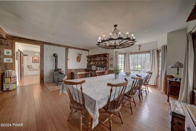 dining room with a chandelier, light hardwood / wood-style floors, and a wood stove