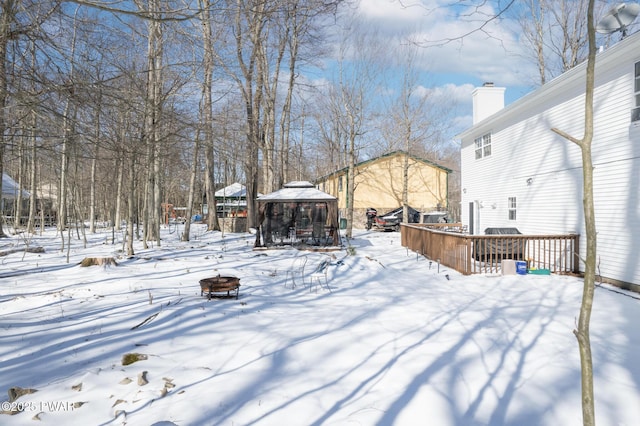 yard layered in snow featuring a gazebo, a deck, and a fire pit