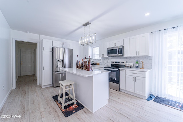 kitchen with appliances with stainless steel finishes, a center island, hanging light fixtures, and white cabinets