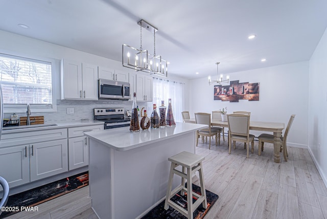 kitchen featuring sink, a center island, light wood-type flooring, pendant lighting, and stainless steel appliances