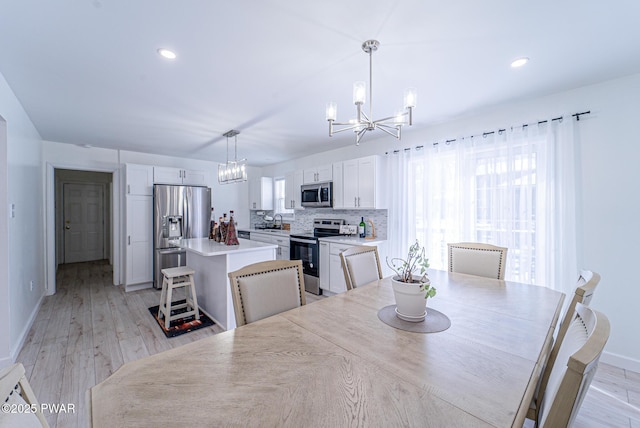 dining area featuring an inviting chandelier, sink, and light hardwood / wood-style floors