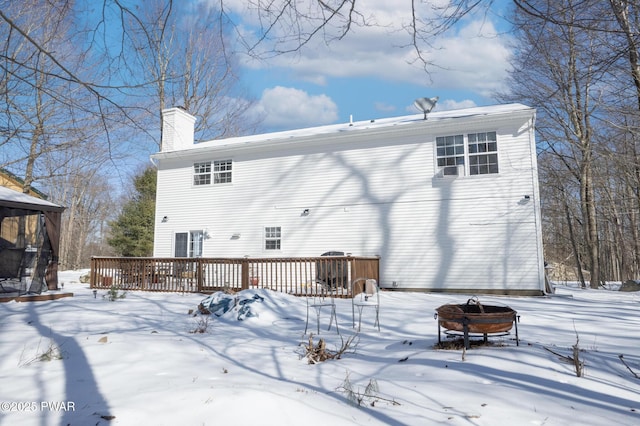 snow covered rear of property featuring a wooden deck and a fire pit