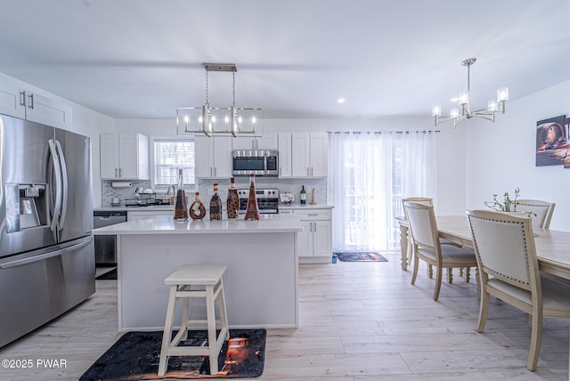 kitchen featuring hanging light fixtures, white cabinetry, appliances with stainless steel finishes, and a kitchen island