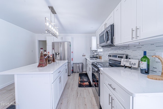 kitchen with appliances with stainless steel finishes, decorative light fixtures, a center island, and white cabinets