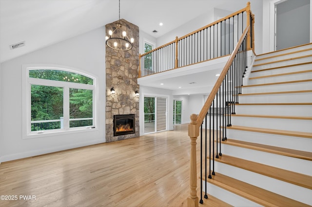120 Milford Estates Dr, Milford, PA 18337 - unfurnished living room with wood finished floors, stairway, high vaulted ceiling, a chandelier, and a fireplace
