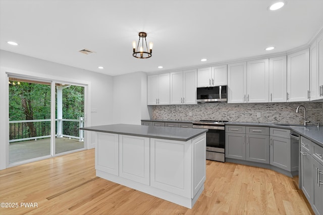 120 Milford Estates Dr, Milford, PA 18337 - kitchen featuring appliances with stainless steel finishes, gray cabinets, dark countertops, light wood-type flooring, and a kitchen island