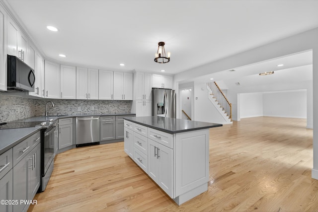 120 Milford Estates Dr, Milford, PA 18337 - kitchen featuring appliances with stainless steel finishes, dark countertops, tasteful backsplash, light wood finished floors, and a kitchen island