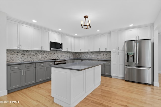 120 Milford Estates Dr, Milford, PA 18337 - kitchen featuring stainless steel appliances, gray cabinetry, dark countertops, light wood-style floors, and decorative backsplash