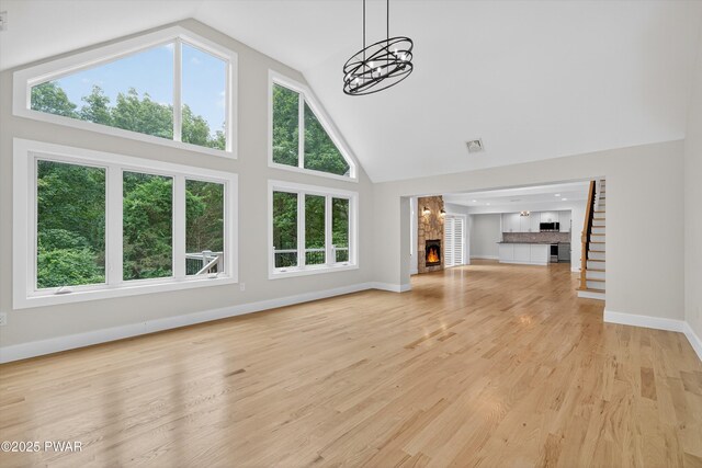 120 Milford Estates Dr, Milford, PA 18337 - unfurnished living room with high vaulted ceiling, a fireplace, a chandelier, and light wood-type flooring