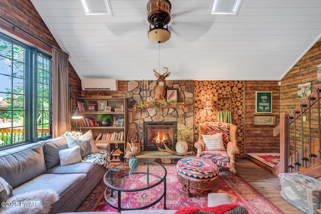 803 Deerfield Rd, Lake Ariel, PA 18436 - living room featuring wood finished floors, vaulted ceiling, a wall mounted AC, a stone fireplace, and stairs