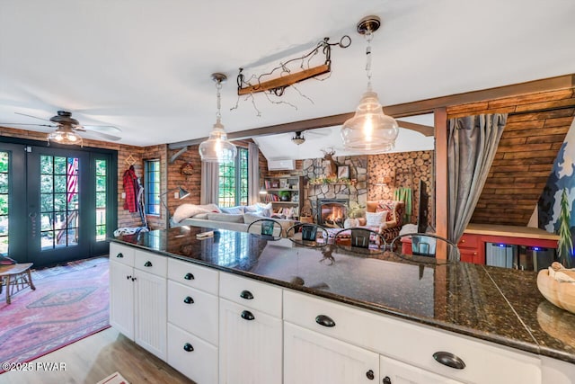 803 Deerfield Rd, Lake Ariel, PA 18436 - kitchen with ceiling fan, hanging light fixtures, white cabinetry, a stone fireplace, and beam ceiling