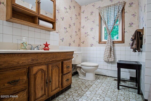 141 Constitution Dr, Lackawaxen, PA 18435 - bathroom with wallpapered walls, vanity, toilet, a wainscoted wall, and tile walls