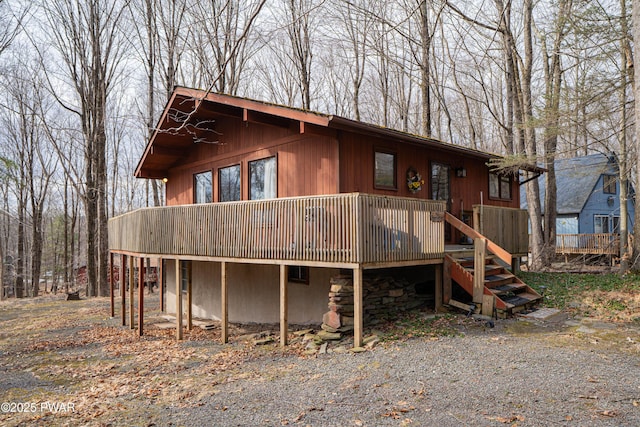 view of front of property featuring stone siding, stairway, and a deck